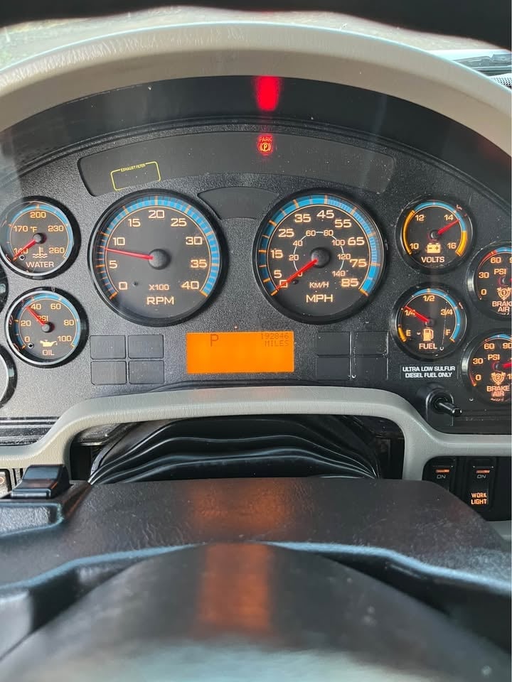 Close-up of a vehicle dashboard showing speedometer, RPM gauge, and warning lights illuminated in red