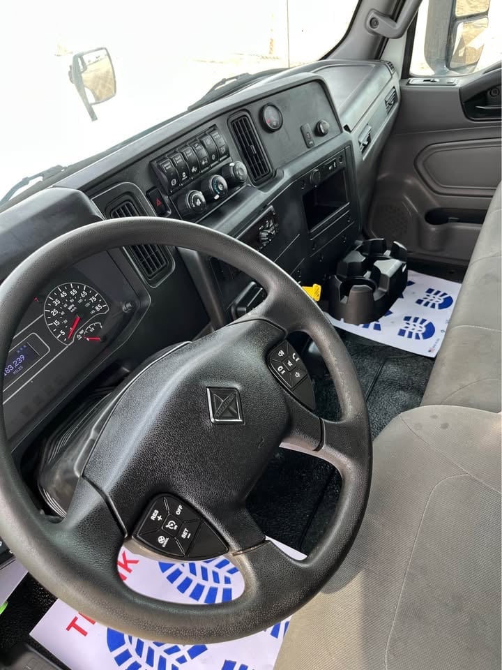 Interior view of a truck cabin showing steering wheel, dashboard, instrument cluster, and center console with controls