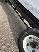 Close-up view of truck tire and side of vehicle on asphalt road