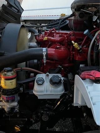 Close-up of a red diesel engine with fuel filters, hoses, and gauges in an industrial truck or heavy equipment setup