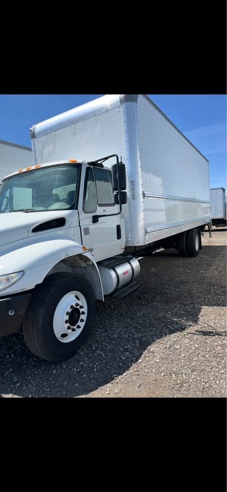 White commercial box truck parked on asphalt lot with clear blue sky in background