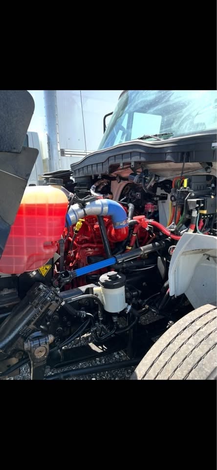 Red diesel engine with blue piping mounted in truck bed, showing industrial engine components and maintenance area