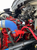 Close-up of a red diesel engine with blue piping, hoses, and mechanical components visible under a truck bed canopy