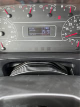 Close-up of a vehicle dashboard displaying odometer reading of 150,239 miles with speedometer, fuel gauge, and digital display screen visible