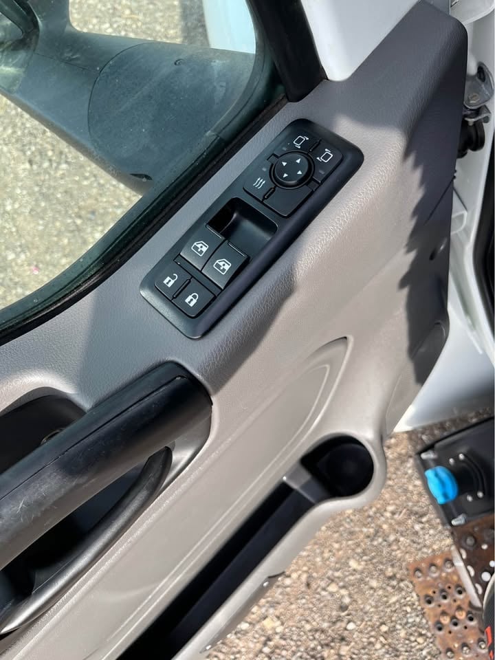 Car door interior showing power window controls and door handle mounted on gray panel